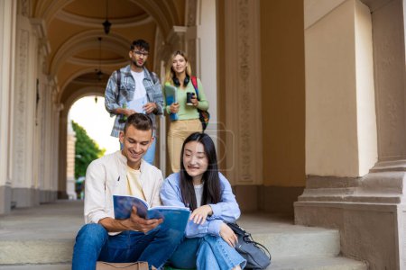 Téléchargez les photos : Les étudiants étudient et passent du temps ensemble à lire un livre assis dans les escaliers du campus. - en image libre de droit