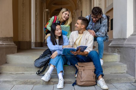 Foto de Grupo de estudiantes que estudian juntos al aire libre, amigos multiétnicos sentados en las escaleras cerca de la universidad. - Imagen libre de derechos