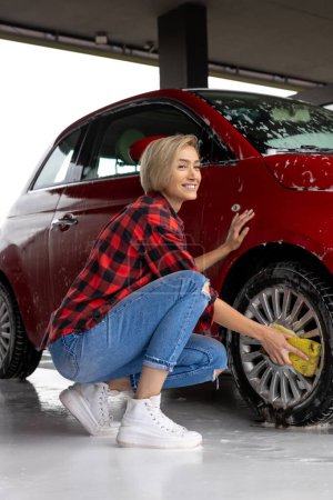 Photo for Car cleaning. Young woman in checkered shirt washing a car - Royalty Free Image