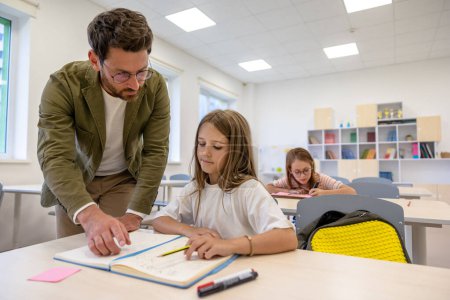 Photo for Brunette man primary school teacher in classroom with pupils. - Royalty Free Image