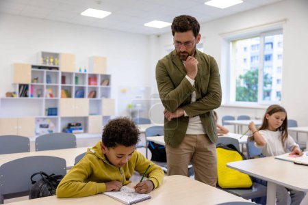 Photo for Brunette man primary school teacher in classroom with pupils. - Royalty Free Image