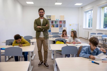 Photo for Young man teacher in classroom with little students. - Royalty Free Image