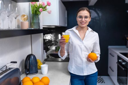 Foto de Hermosa mujer joven haciendo jugo de naranja fresco en la cocina. - Imagen libre de derechos