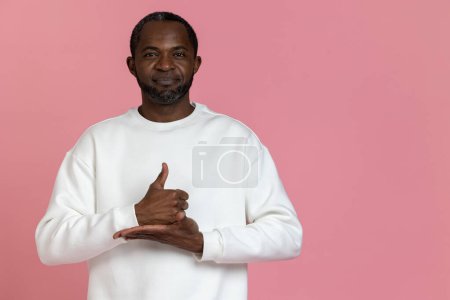 Photo for Black man wearing white sweatshirt using sign language isolated over pink background. - Royalty Free Image