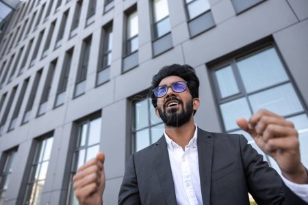 Photo for Waist up of an excited successful hindu businessman near the office building - Royalty Free Image