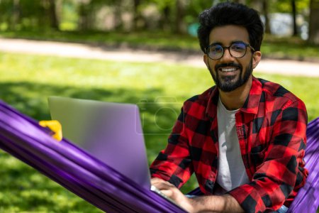 Téléchargez les photos : Barbu jeune homme brune travaillant sur ordinateur portable en plein air - en image libre de droit