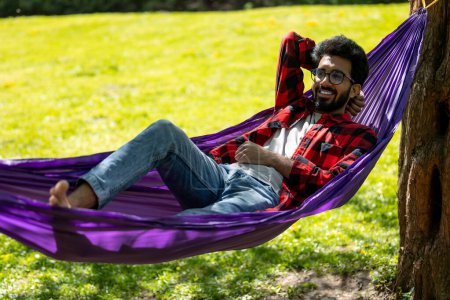 Téléchargez les photos : Homme dans l'hamac regardant détendu et satisfait - en image libre de droit