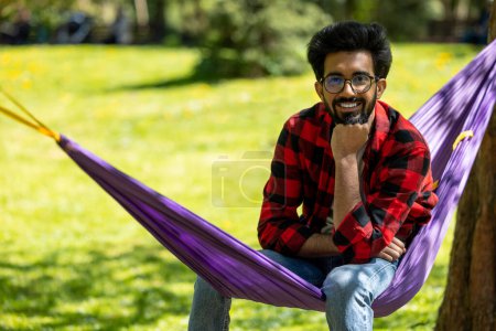 Téléchargez les photos : Jeune homme hindou se sentant détendu et heureux dans le parc - en image libre de droit