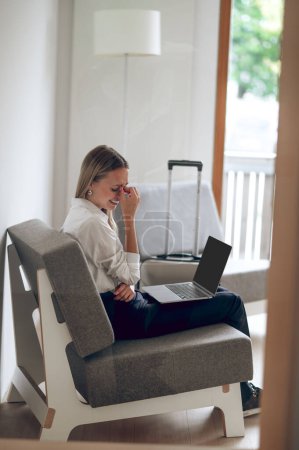 Téléchargez les photos : Femme en pleurs avec ordinateur portable à la recherche d'un nouvel appartement dans Internet assis dans sa maison. - en image libre de droit