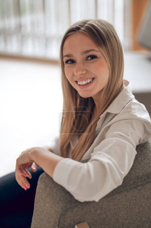 Téléchargez les photos : Belle femme aux cheveux blonds assise dans son appartement moderne. - en image libre de droit