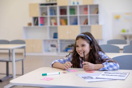 Foto de Niño inteligente niña pequeña sentada en el escritorio niño pequeño escritura preparación tarea escolar asignación. - Imagen libre de derechos