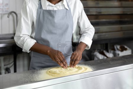 Téléchargez les photos : Jeune femme afro-américaine préparant une pizza dans la cuisine - en image libre de droit