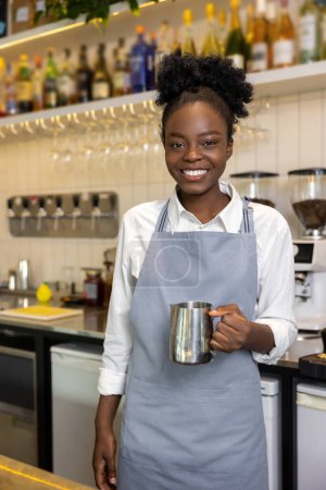 Foto de Barista femenina de piel oscura sonriente con una cafetera - Imagen libre de derechos