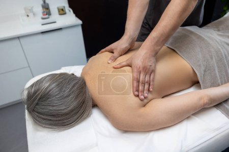 Téléchargez les photos : Massage du dos. Gros plan d'une patiente qui se fait masser le dos dans une clinique - en image libre de droit