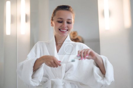 Foto de Buenos días. Mujer joven en bata blanca limpiando dientes - Imagen libre de derechos