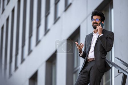 Photo for Brunette hindu young man on the building background with phone in hand - Royalty Free Image