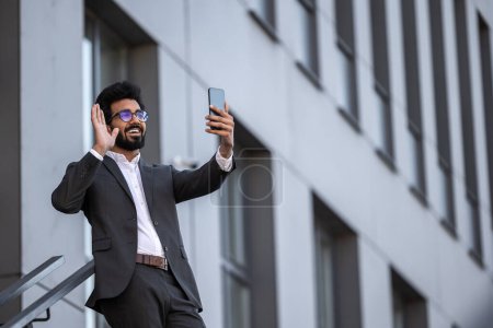 Photo for Brunette hindu young man on the building background with phone in hand - Royalty Free Image