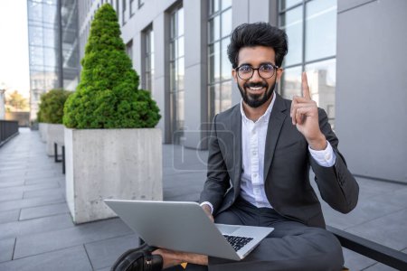 Téléchargez les photos : Homme d'affaires travaillant sur un ordinateur portable près de l'immeuble de bureaux - en image libre de droit