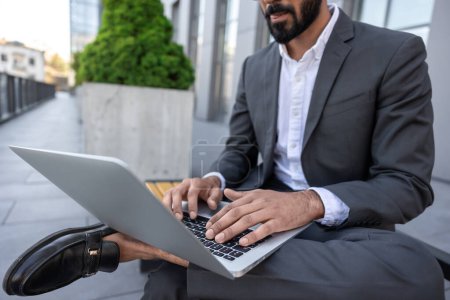 Photo for Businessman working on laptop near the office building - Royalty Free Image