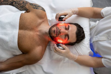 Photo for Phototherapy. Dark-haired bearded man receiving phototherapy in a clinic - Royalty Free Image