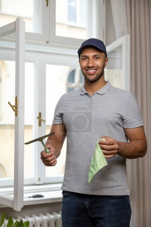 Téléchargez les photos : Jeune homme lave-vitre à la maison avec raclette essuie-glace. - en image libre de droit