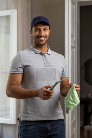 Téléchargez les photos : Adulte homme lavage fenêtre faire ménage corvées à la maison tenant essuie-glace raclette et chiffon. - en image libre de droit