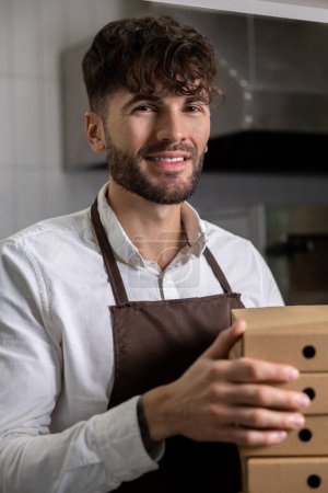 Téléchargez les photos : Homme de service avec de nombreuses boîtes à pizza dans la pizzeria - en image libre de droit