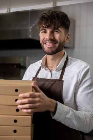 Téléchargez les photos : Travailleur de pizzeria dans tablier préparation de pizza pour le service de livraison - en image libre de droit