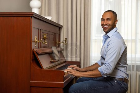 Foto de Hombre alegre practicando el piano en el salón de su casa relajándose del trabajo - Imagen libre de derechos