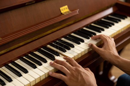 Téléchargez les photos : Homme méconnaissable assis au piano et jouant de la musique à la maison - en image libre de droit