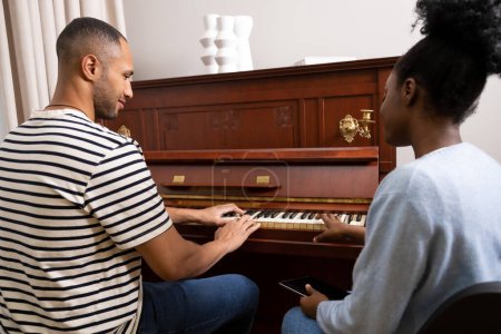 Téléchargez les photos : Homme et femme adultes assis au piano jouant de la musique à la maison - en image libre de droit