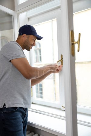 Photo for Professional bearded handyman fixing window handle at home. - Royalty Free Image