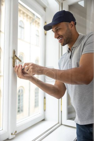 Photo for Professional bearded handyman fixing window handle in his apartment. - Royalty Free Image