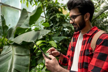 Téléchargez les photos : Homme hindou avec tablette dans les mains dans le jardin botanique - en image libre de droit