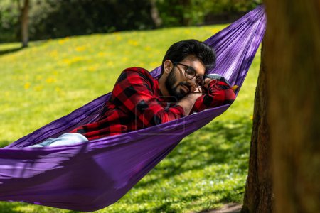 Photo for Brunette young man sleeping in hammock in the park - Royalty Free Image