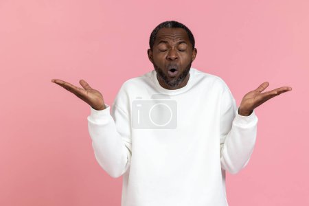 Photo for Shocked black man wearing white sweatshirt shrugging shoulders isolated over pink background. - Royalty Free Image