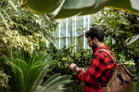 Téléchargez les photos : Jeune homme en chemise à carreaux dans un jardin botanique - en image libre de droit