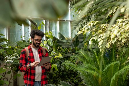 Téléchargez les photos : Jeune homme en chemise à carreaux dans un jardin botanique - en image libre de droit