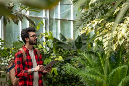 Junger Mann im karierten Hemd in einem botanischen Garten