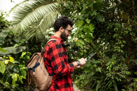 Photo for Dark-haired hindu man with backpack walking in botanical garden - Royalty Free Image
