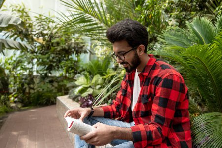Téléchargez les photos : Jeune homme lisant un livre et regardant impliqué - en image libre de droit
