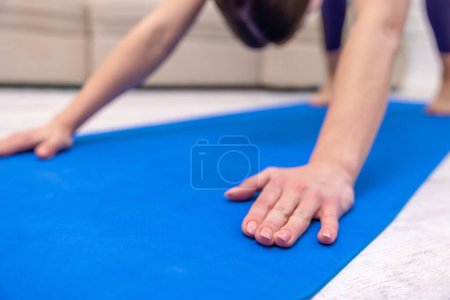 Téléchargez les photos : Yoga à la maison. Jeune femme debout dans la pose de chien vers le bas - en image libre de droit