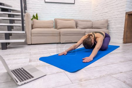 Téléchargez les photos : Yoga à la maison. Fille dans une pose de bébé faisant du yoga à la maison - en image libre de droit
