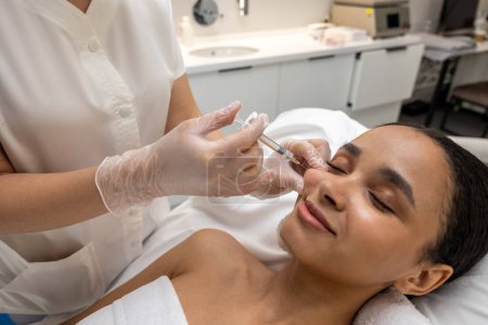 Foto de En el salón de belleza. esteticista haciendo inyecciones faciales a una paciente femenina - Imagen libre de derechos