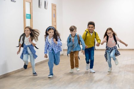 Photo for Group of elementary school kids running in school corridor during break. - Royalty Free Image