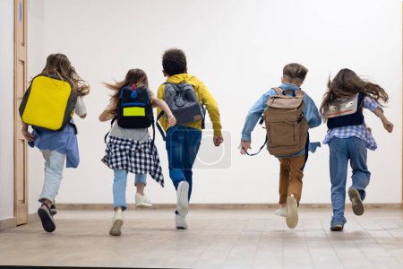 Téléchargez les photos : Groupe d'enfants de l'école primaire courant dans le couloir de l'école pendant la pause. - en image libre de droit