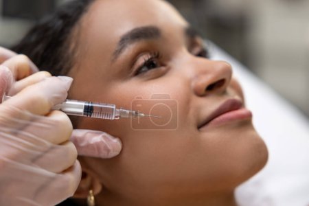 Photo for Mesotherapy. Young dark-skinned woman having a session of mesotherapy - Royalty Free Image
