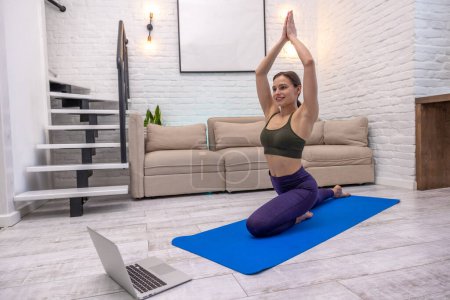 Téléchargez les photos : Yoga à la maison. Jeune femme assise dans une pose de pigeon et l'air détendu - en image libre de droit