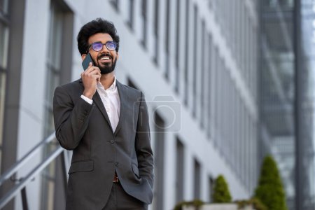 Foto de Hombre de negocios hindú teniendo una llamada telefónica y buscando confiado - Imagen libre de derechos
