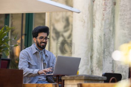 Photo for Working. Dark-haired young hindu man working on laptop in a cafe - Royalty Free Image
